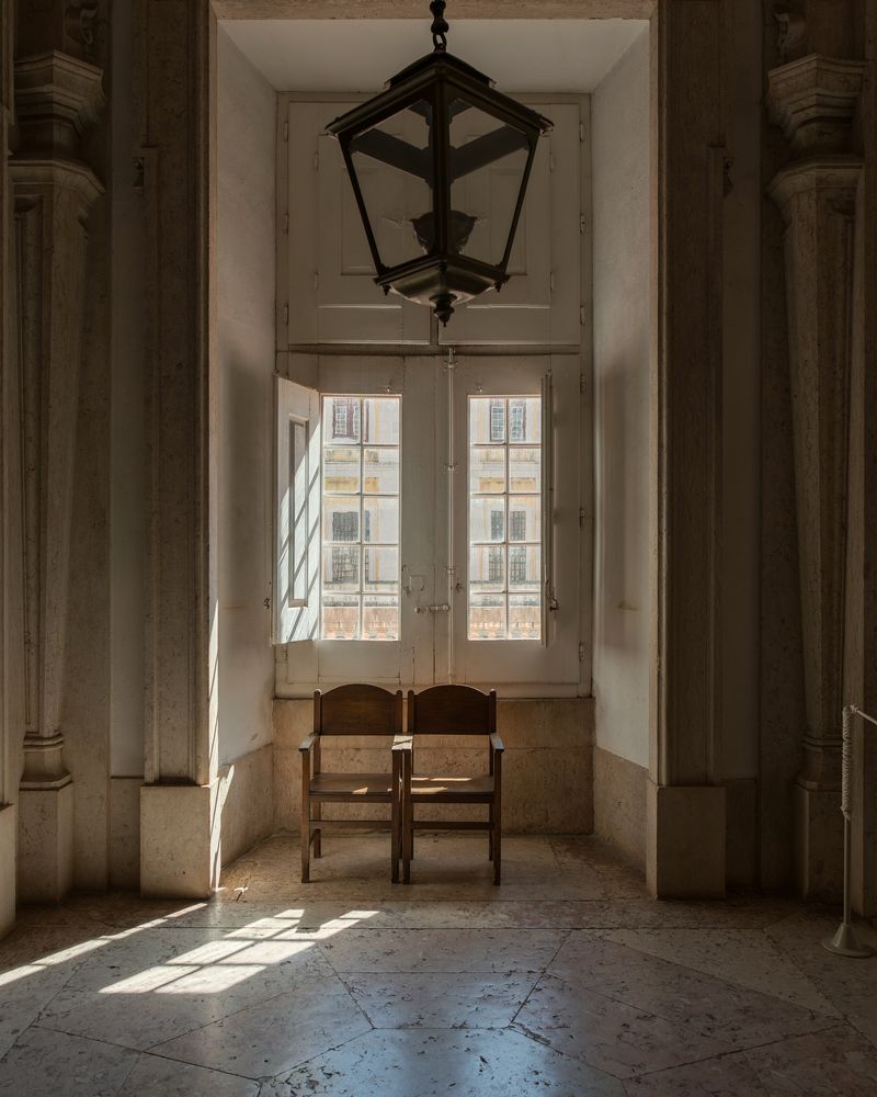 Two chairs beneath a tall window in a stone-walled room