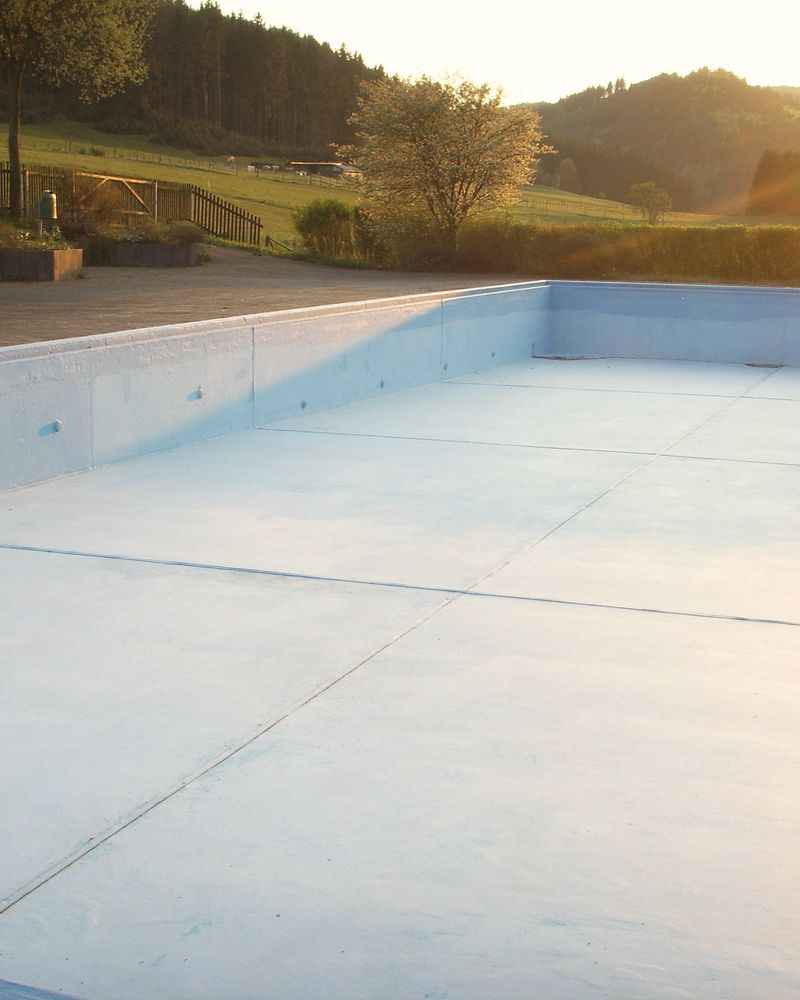 An empty open-air swimming pool in low evening sun