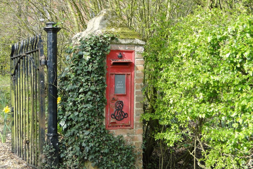 An old red postbox set into a garden wall among ivy