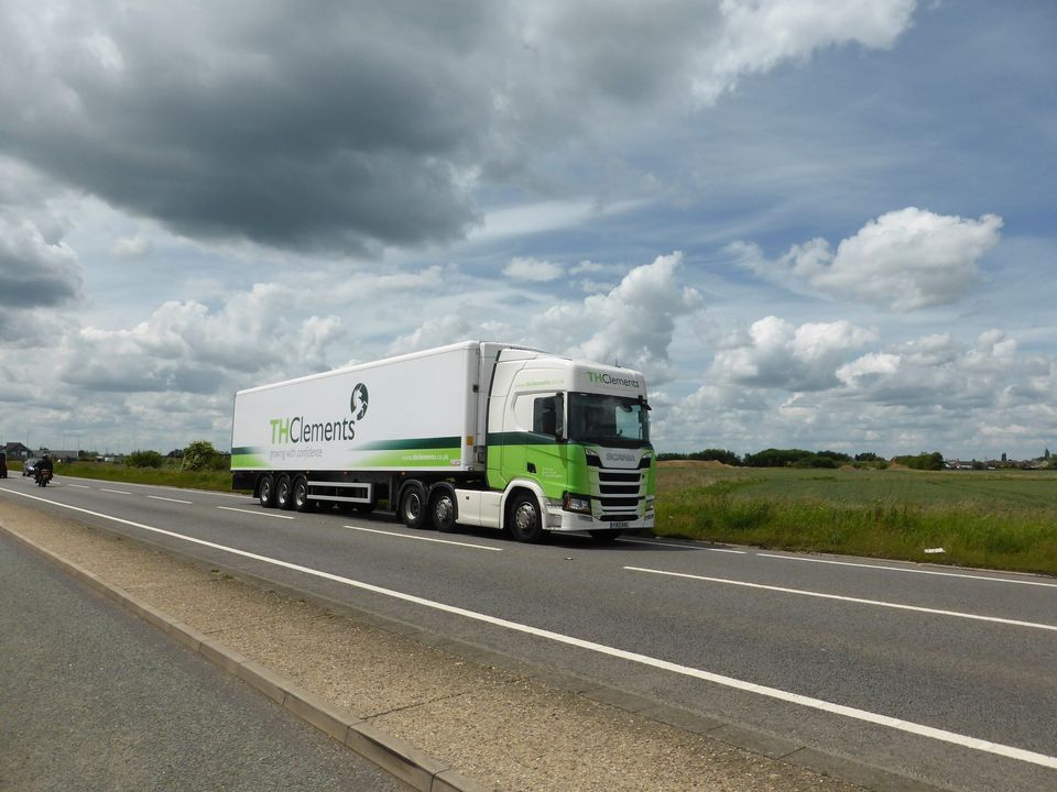 White articulated lorry on a dual carriageway under a cloudy sky
