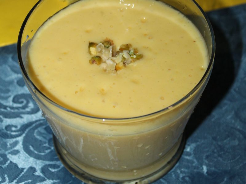 A glass of mango lassi on a blue cloth