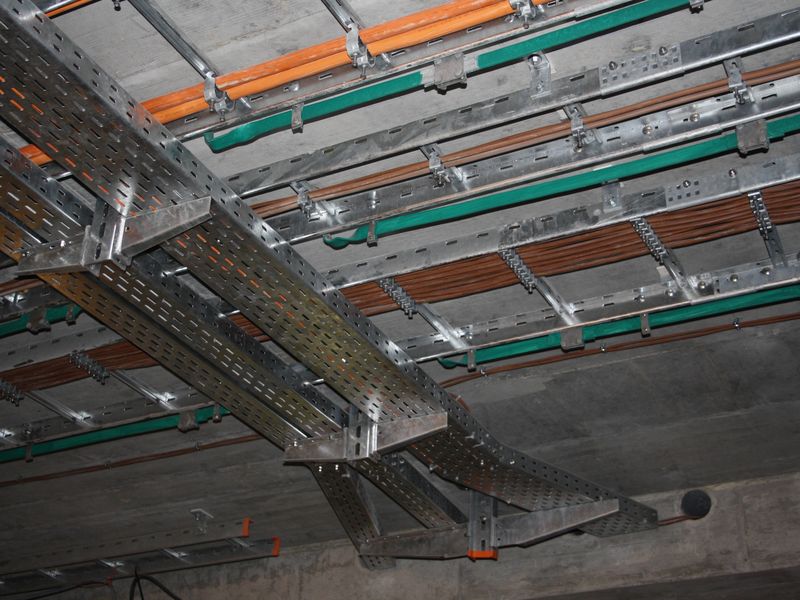 Cable ladders carrying cables along a concrete ceiling