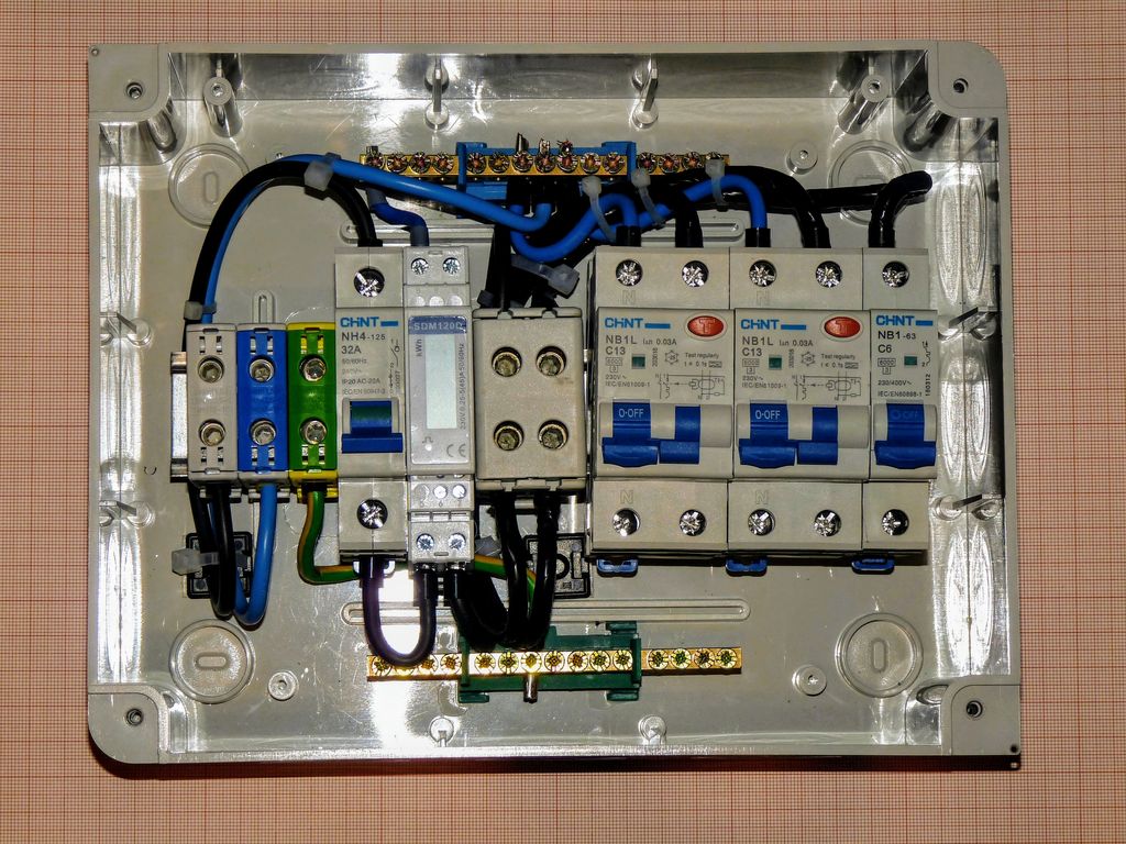 An open consumer unit with a row of circuit breakers and neatly dressed blue and brown wiring