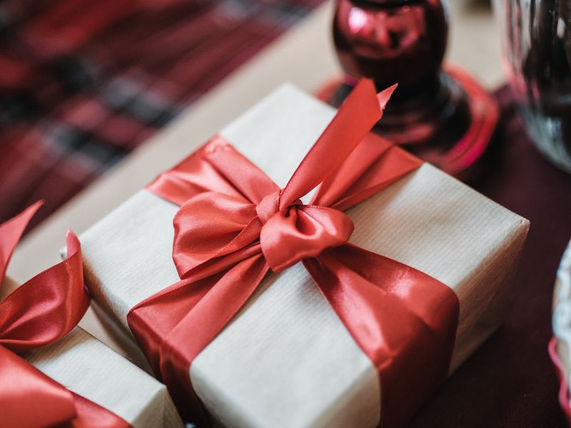 A brown gift box tied with a red ribbon and bow