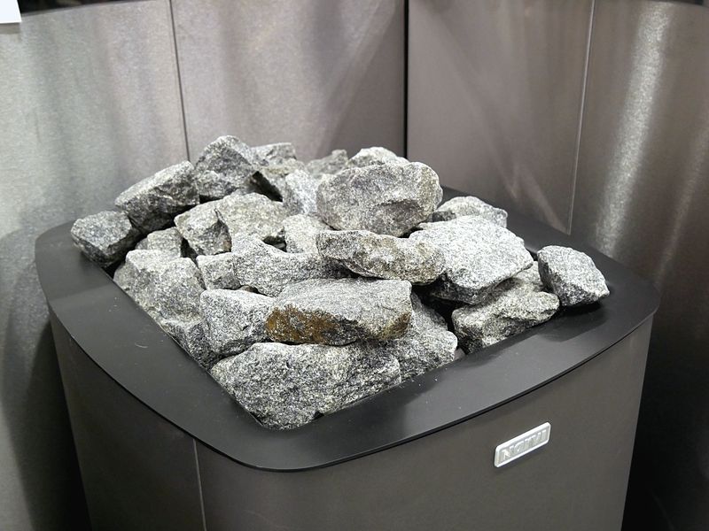 A wooden sauna bench beside a stove of heated stones