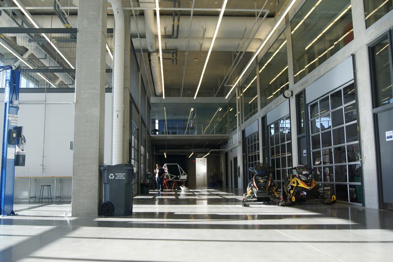 A long, brightly lit workshop hall with car lifts along one side