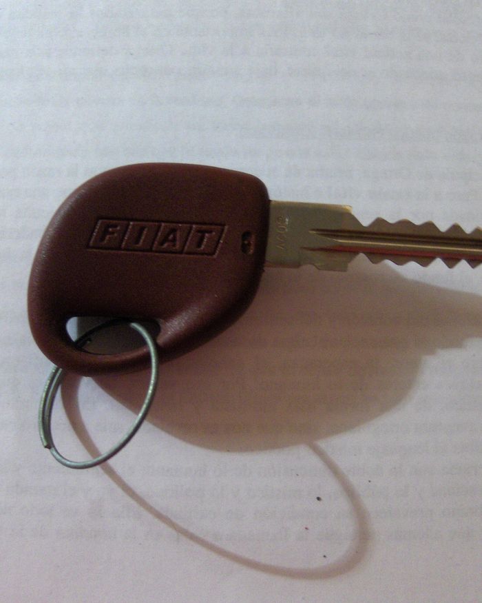 A car key with a brown plastic head and a key ring on a white surface