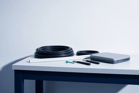 Workshop bench with coiled cable, conduit and face-down test equipment.