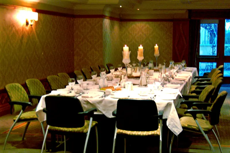 A long candlelit table set for a reception dinner in a dim room