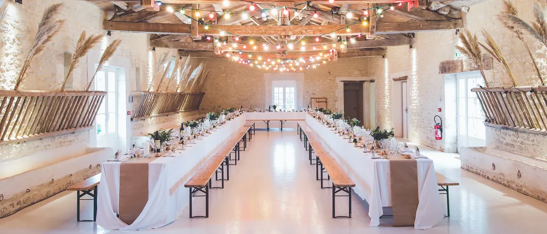 A long hall with timber roof beams, set with long reception tables and benches