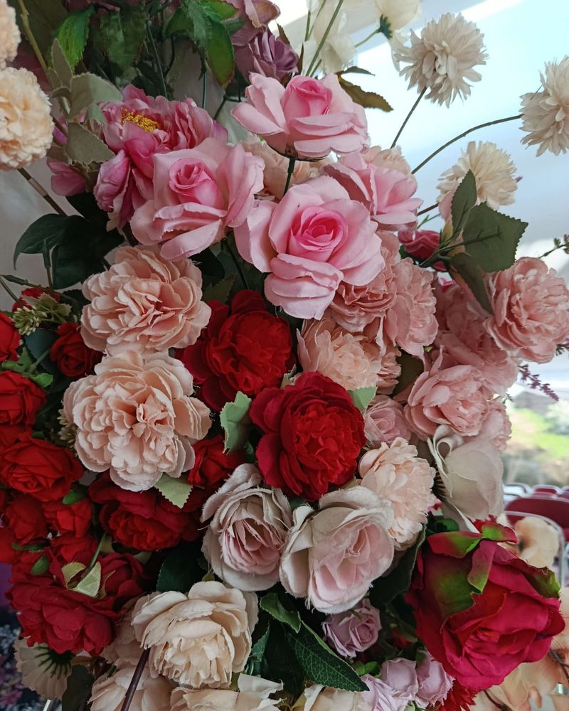 A dense wall of pink, red, cream and white roses arranged as wedding decoration