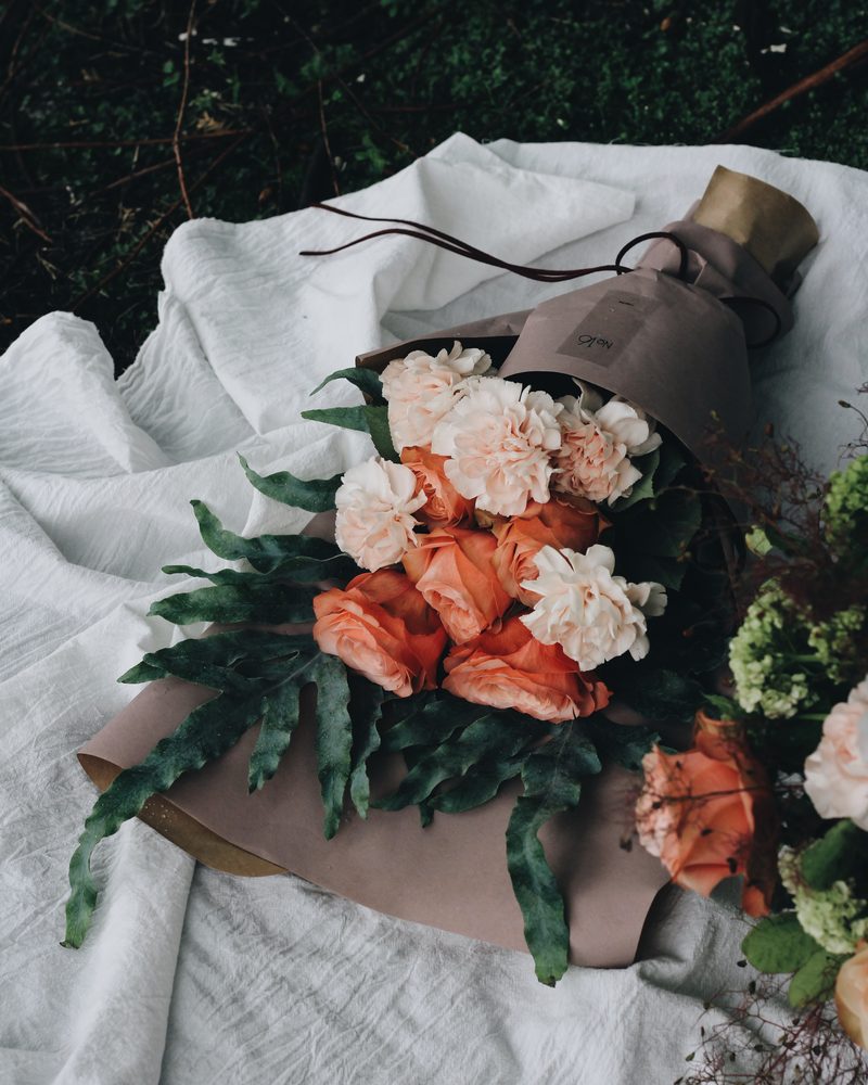 Bouquets of pink and peach carnations wrapped in paper on a white cloth