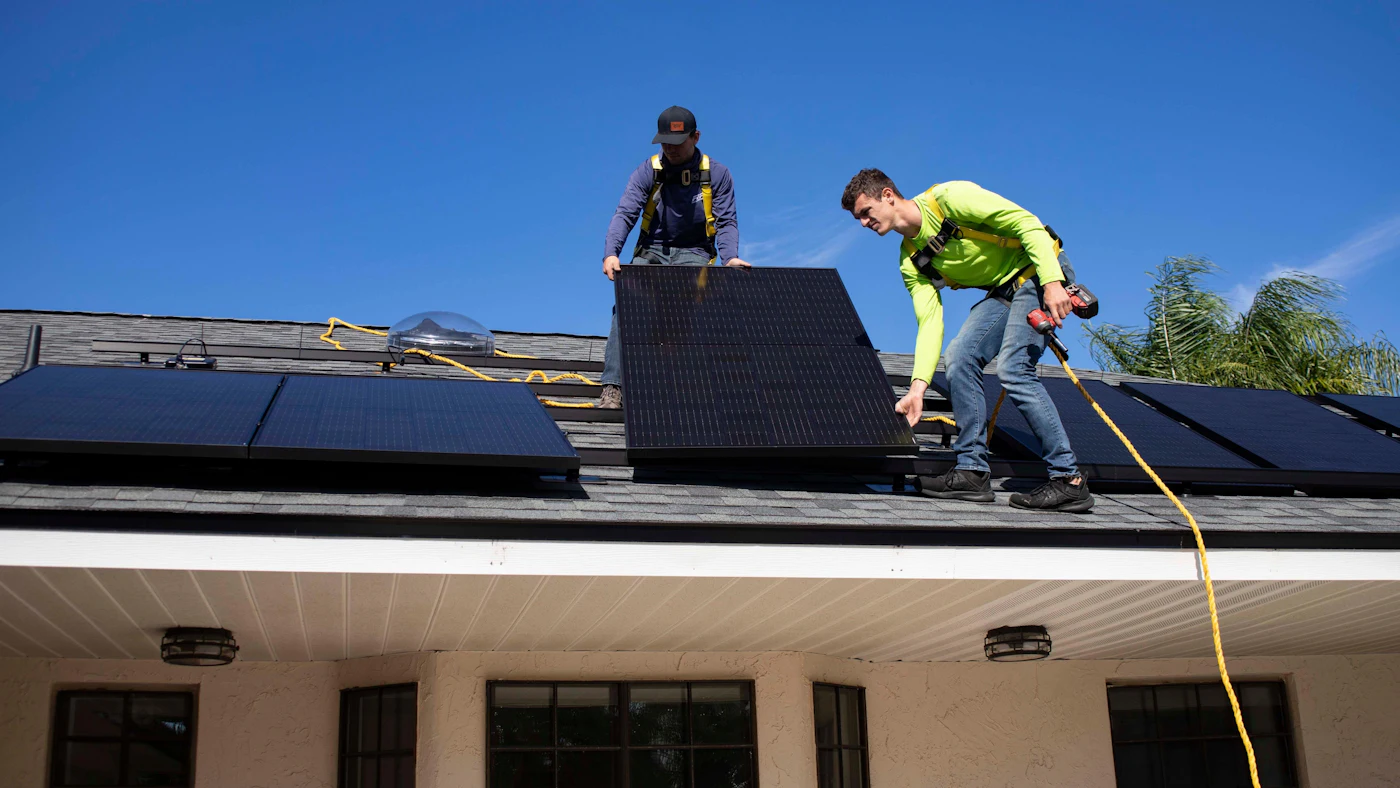 Two installers fitting panels on a house roof