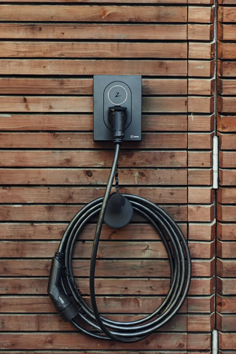 A wall-mounted car charger with its cable coiled