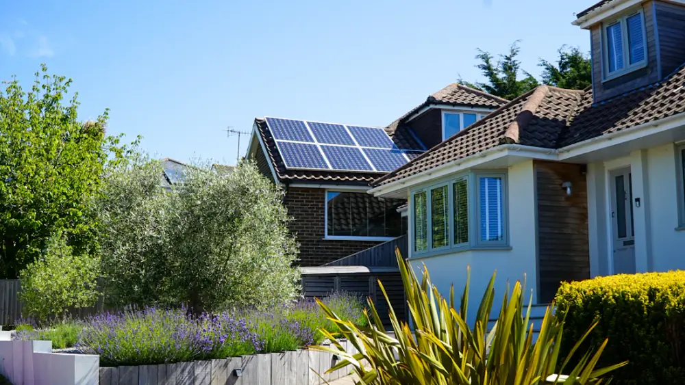 A house with solar panels on its roof and a garden in front