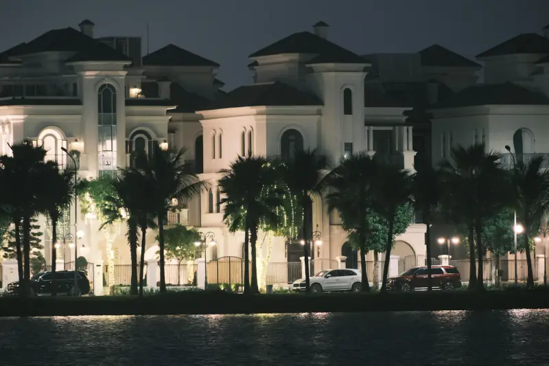 A Mediterranean villa with palm trees, lit at night